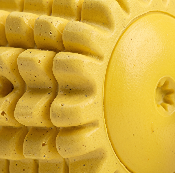 Close-up of a textured yellow dog toy with a circular hole.