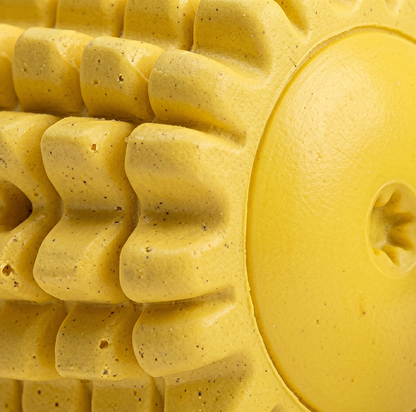 Close-up of a textured yellow dog toy with a circular hole.