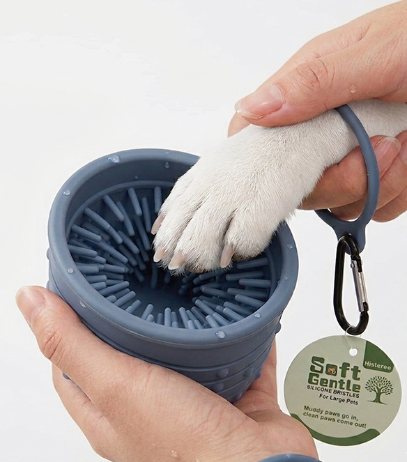 Pet paw cleaning tool with a paw being cleaned, held by a hand, on a white background.