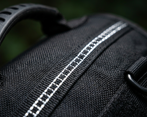 Close-up of a black dog harness with white stitching on a dark background